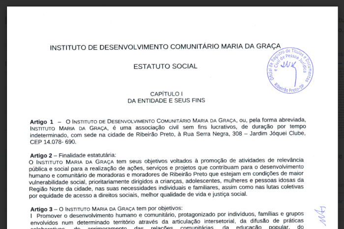 Imagem da primeira página do Estatuto, uma folha de fundo branco e letras em preto, com o título Instituto de Desenvolvimento Comunitário Maria da Graça - Estatuto Social e o texto dos artigos iniciais, contendo uma figurinha azul onde aparece escrito em cículo Oficial de Registro de Títulos e Documentos e Civil de Pessoa Jurídica - Ribeirão Preto-SP